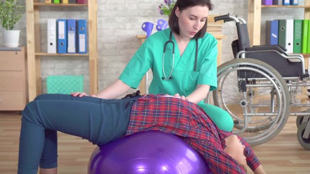 Physiotherapist in the rehabilitation center helps a teenage girl in rehabilitation after an injury close up