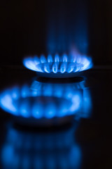 two blue gas flames of a stove in the dark