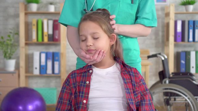 physical therapist in rehab is doing the treatment on the neck of the girl adolescent close up