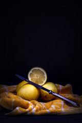 YELLOW LEMONS ON KITCHEN CLOTH AND DARK BACKGROUND.