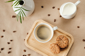 coffee with milk and oatmeal cookies on a wooden tray