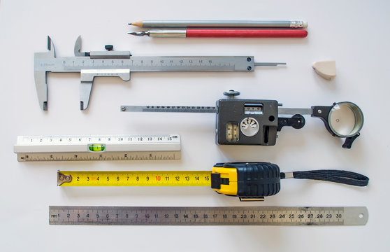 Measuring instruments and tools insulated on a white sheet. Set with various rulers, planimeter, caliper, pencil, ink pen for use in manufacturing process industrial sector.