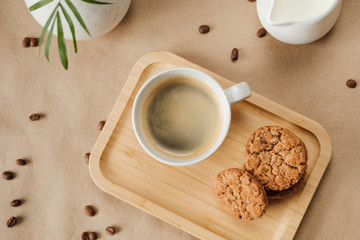 black coffee with milk and oatmeal cookies on a wooden tray