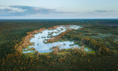 Warmly colored sunrise over a foggy swamp. Aerial view of stunning landscape at peat bog at Cenas...