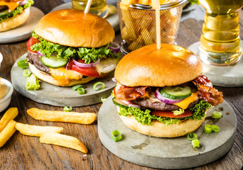 close-up view of tasty burgers, glasses of beer and french fries on table 