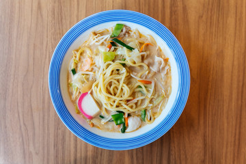 Top view of Champon Ramen (a noodle dish that is a regional cuisine of Nagasaki, Japan) with Pork, Shrimp, Scallion, Sprout, Carrot, Cabbage, Corn and Kamaboko.