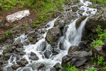 A powerful mountain stream flows down from the rocks in a dense fog.