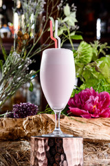 milkshake in beautiful glass on the background of fresh flowers. Summer drink