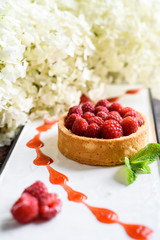 Obraz na płótnie Canvas raspberry tart on a white plate on a dark wooden background