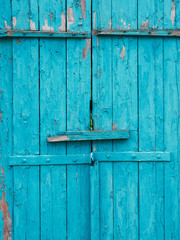 Old turquoise painted wooden doors with peeled faded paint
