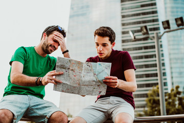 .Two attractive and young boys lost in the city while they vacation. Using a map to get their bearings in Madrid. Travel photography. Lifestyle