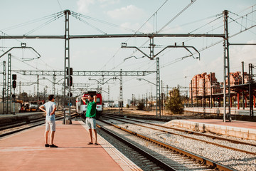 Naklejka premium .Two young brothers on the platform missing their train. Relaxed and carefree about starting their vacation. Lifestyle. Travel photography