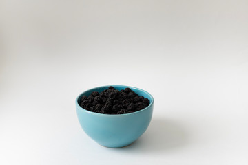Fototapeta na wymiar Black raspberry in a blue bowl. Organic raspberry on light background with copy space for text. Blackberry isolated