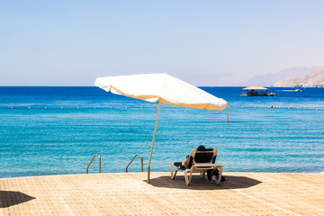 outdoor summer vacation concept photography of hotel resort territory with beach, white umbrella and lounge near Red sea   