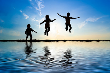 Silhouette of kids jumping over sun rising up