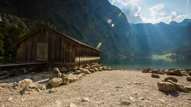 Timelapse of clouds passing over a wooden boathouse on the shore of Obersee lake, Bavaria, Germany