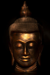 Fototapeta na wymiar the head of the Buddha statue in gold on a black background
