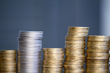 Close-up of columns of multi-colored coins of increasing height, the concept of saving and saving money, selective focus