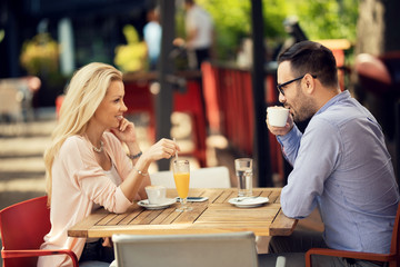 Happy couple talking to each other while relaxing in a cafe.