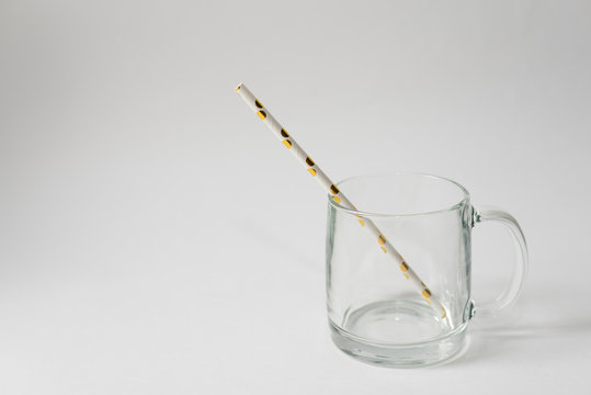 Striped straw for cocktails in a empty cup on a white background isolated. Copy space