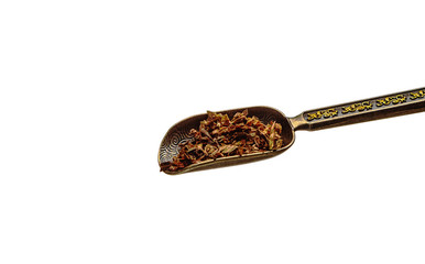 Chinese copper vintage teaspoon with gilded pattern with black tea leaves on white background
