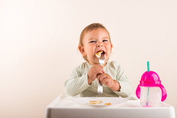 Baby toddler eating pancakes with fork. Isolated. Copy space
