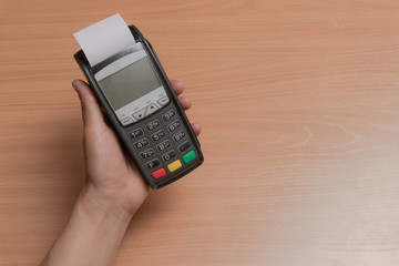 A person holds in his hand a terminal for paying for purchases in a store using bank cards or NFC
