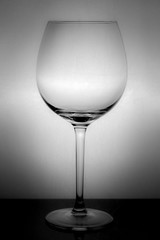 large glass, empty red wine glass on a white background with reflection and highlights on the edges