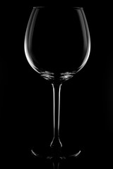 large glass, empty red wine glass on a black background with reflection and highlights on the edges