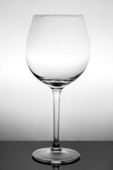 large glass, empty red wine glass on a white background with reflection and highlights on the edges