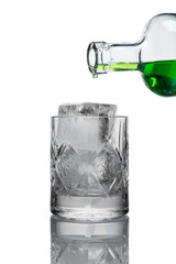 on a white background with a reflection is a glass glass glass filled with ice, it flows from a glass bottle of green lemonade (drink)