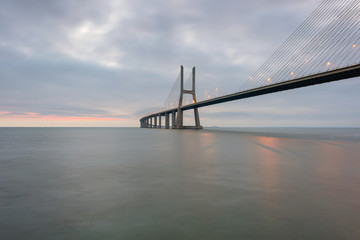 Urban landscape at sunrise. Lisbon is an amazing tourist destination. The Vasco da Gama Bridge is a beautiful landmark, and one of the longest bridges in the world. Portugal in a dawn light.