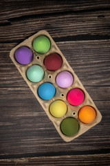 colorful eggs lie in a pack of 10pcs eggs on a background of aged dark wood