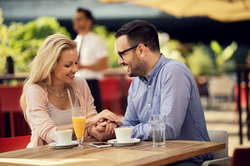 Happy couple in love holding hands in a cafe.