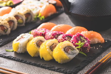 Sushi Set sashimi and sushi rolls served on stone slate
