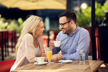 Happy couple communicating while having a date in a cafe.