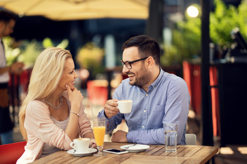 Happy man talking to his girlfriend while drinking coffee in a cafe.