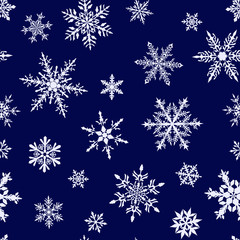 Fototapeta na wymiar Christmas seamless pattern of complex big and small snowflakes in white colors on blue background