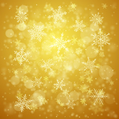 Christmas background of complex blurred and clear falling snowflakes in yellow colors with bokeh effect