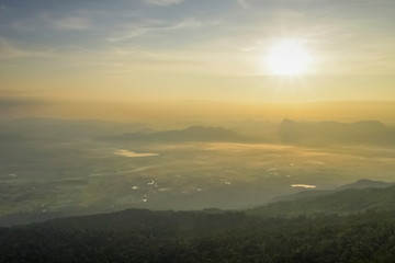 Fototapeta na wymiar Mountain view morning of top hill around with soft fog and yellow sun light in the sky background, sunrise at Nok Aen Cliff, Phu Krakueng National Park, Loei, Thailand.