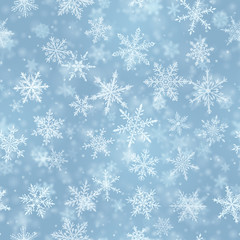 Christmas seamless pattern of complex blurred and clear falling snowflakes in light blue colors with bokeh effect