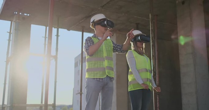 Waist up portrait of two modern construction workers using VR gear to visualize projects on site, copy space.