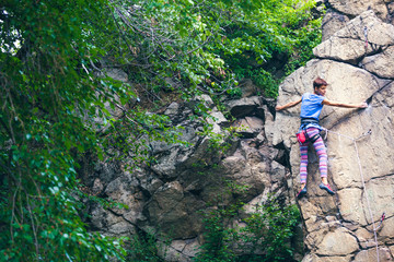 The girl climbs the granite rock.