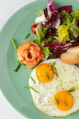 Top view of perfect fried couple of eggs with smoked salmon, mixed green salad and crunchy croutons with soft butter