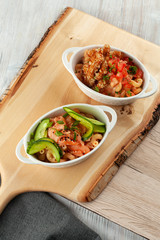 Wooden board with mac and cheese with different toppings: salmon and cucumber, chicken strips with tomatoes