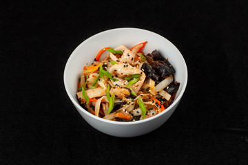 Thai wok wheat noodle with bell pepper, onion, omelette and shiitake mushrooms, isolated on black background
