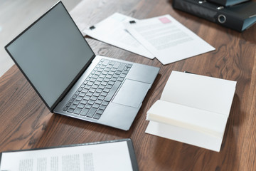 Modern laptop and documents on wooden table