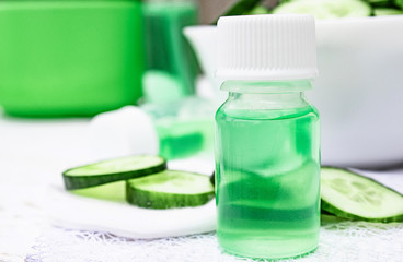 Sliced cucumber and a bottle of cucumber extract. Liquid cosmetics for skin care.