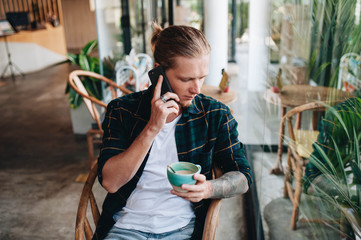 Young man drinking coffee and talking on the phone
