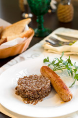 Fototapeta na wymiar Fried Meat sausages on a plate with buckwheat porridge on dark wooden table
